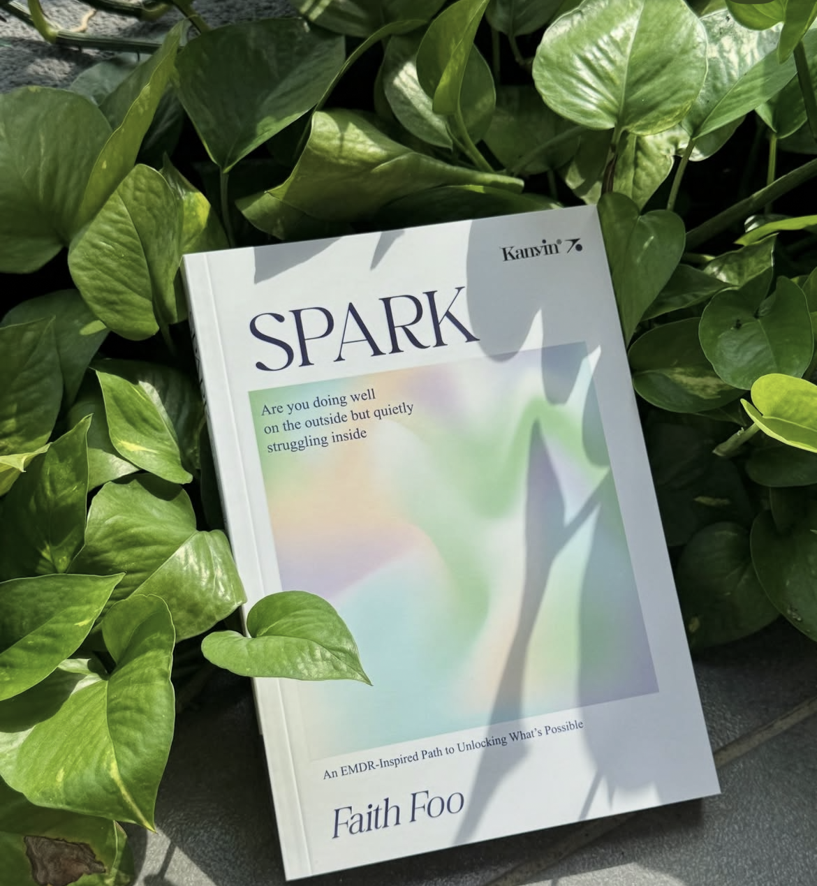 SPARK book by Faith Foo resting among green leaves